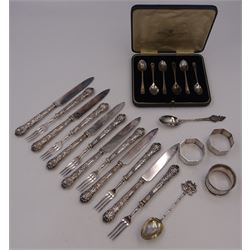 Set of 1930s silver handled fruit knives and forks, for six place settings, the handles decorated in relief with fruiting vines, hallmarked Walker & Hall, Sheffield 1934, together with a set of six 1920s silver egg spoons, with pin prick engraving to handle, hallmarked Thomas Bradbury & Sons Ltd, Sheffield 1929, in fitted case, three silver napkin rings, to include a pair, of octagonal form, with floral engraving, hallmarked John Rose, Birmingham 1951 and two silver souvenir spoons