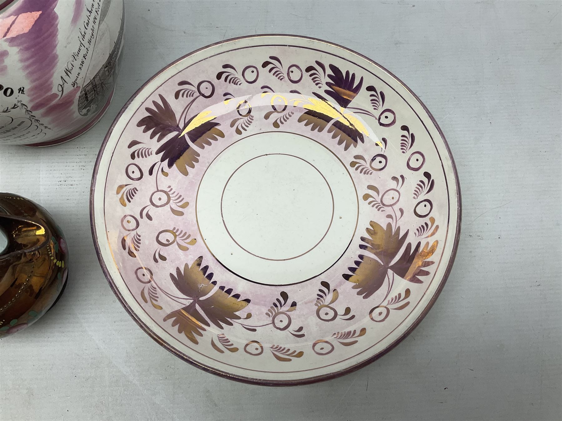 Early 20th century Sunderland lustre jug, decorated with transfer Masonic scene and poem 'The World is in Pain/Our Secrets to Gain/But Still Let Them Wonder and Gaze/The Never Can Divine/The World Nor The Sign/Of a Free and Accepted Mason', the reverse decorated with Sunderland River Wear cast iron bridge scene below text (a/f), together with a copper lustre jug, and pink lustre bowl, jug H20cm