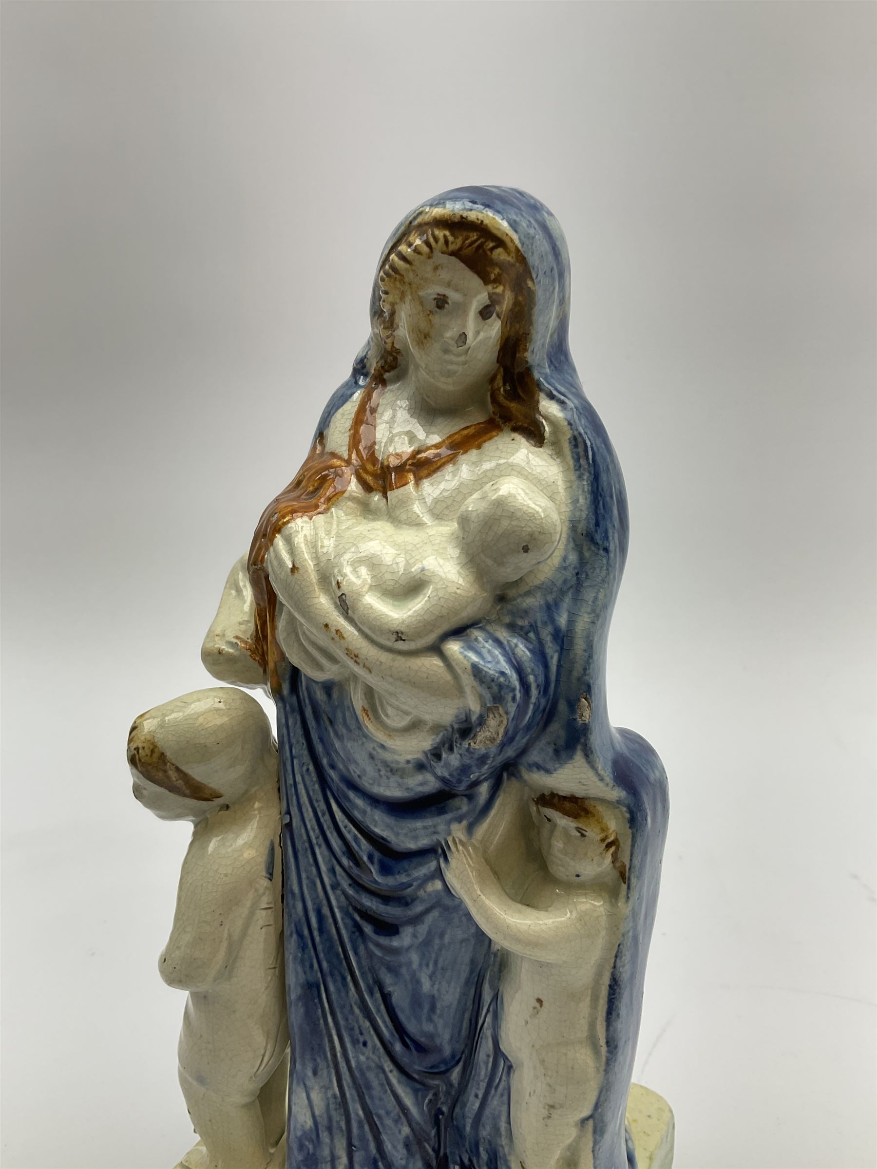 Late 18th century Prattware figure representing Charity, modelled as a mother with baby in her arms and two small children clutching at her robes, upon a square base, overall H21cm.