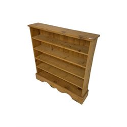 Traditional pine low open bookcase, fitted with four shelves on shaped plinth base