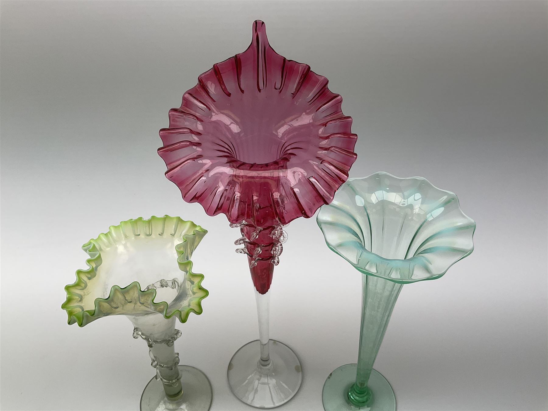 A Victorian Vaseline glass trumpet vase, with crimped rim and trailed frilled decoration, H26cm, together with a 20th century example, and a Victorian cranberry glass Jack-in-the-pulpit vase. (3). 