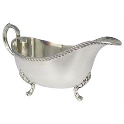 Mid 20th century silver sauce boat, with oblique gadrooned border to rim and scroll handle, upon three foliate mounted paw feet, hallmarked Sheffield 1965, makers mark HH, including handle H9cm, approximate weight 6.91 ozt (215 grams)