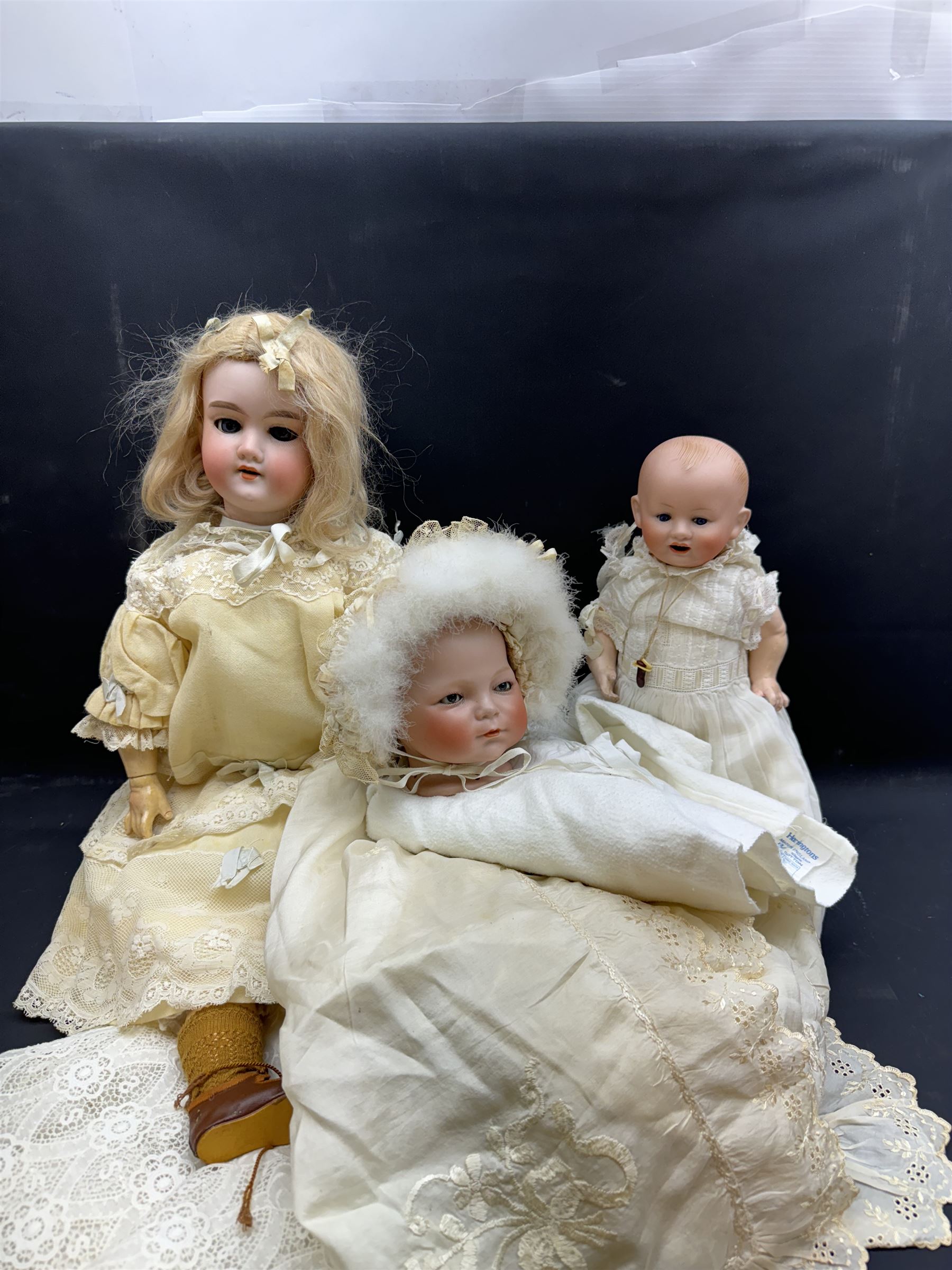 Two German bisque head dolls, to include a Franz Schmidt example with blue glass eyes and an Armand Marseille 590 example with applied hair, together with a Schoenau & Hoffmeister bisque doll's head, pair of doll's hands and a collection of clothing