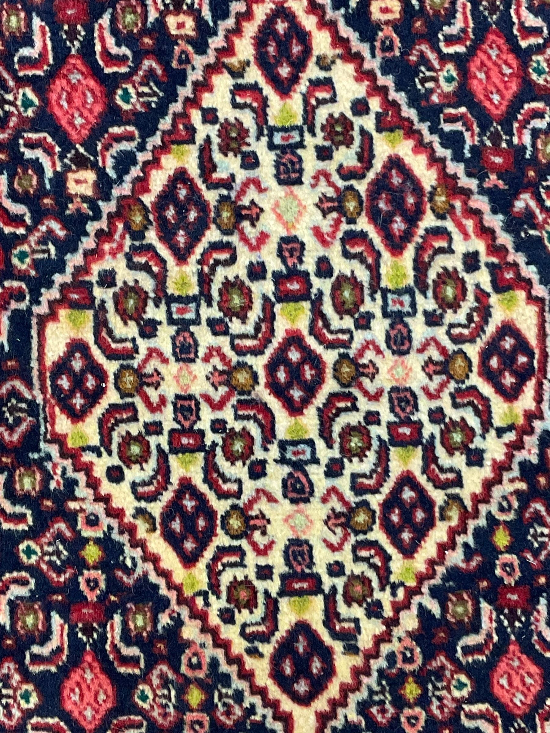 North West Persian Senneh indigo and crimson ground runner, the Herati decorated field with five interconnected lozenges, triple band border with repeating flower head motifs 