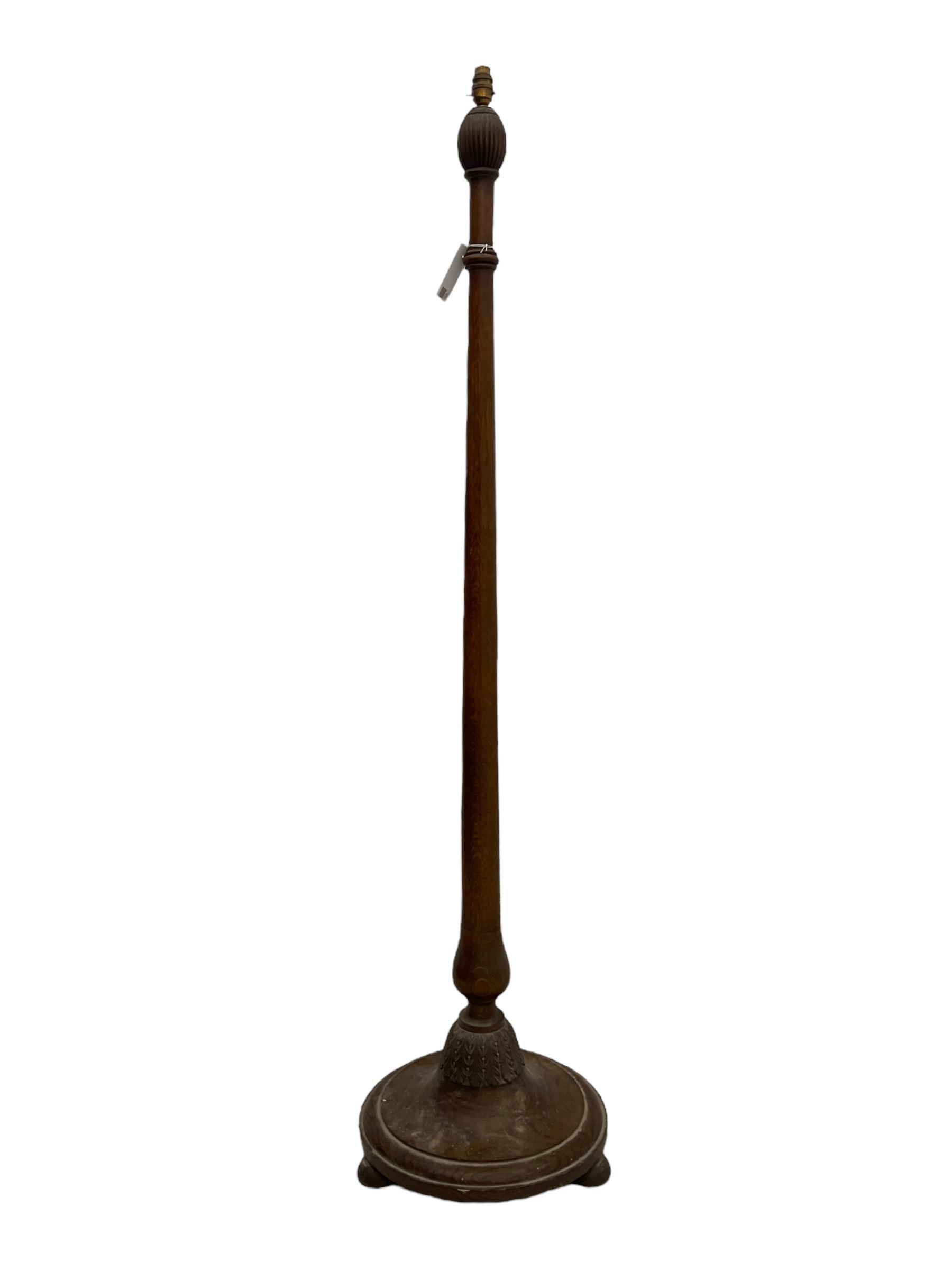 Early 20th century oak standard lamp base, of baluster form with fluted acorn finial and carved foliate decoration to the base, raised on circular plinth with bun feet