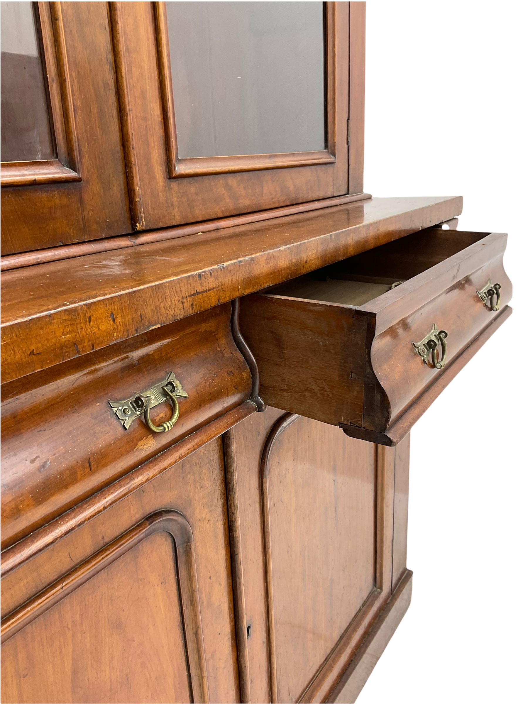Victorian mahogany bookcase on cupboard, projecting cornice over two glazed doors and carved corbels, fitted with two drawers and double cupboard, plinth base