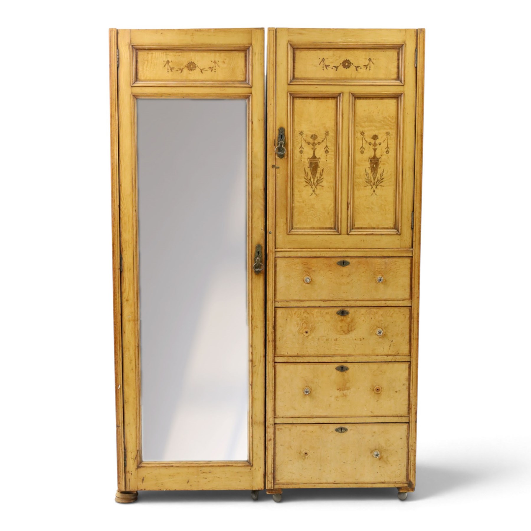 Edwardian Neoclassical figured ash and inlaid double combination wardrobe, the left section with mirrored door enclosing a hanging rail, the right section with cupboard door above four graduated drawers with glass knobs, raised on castors