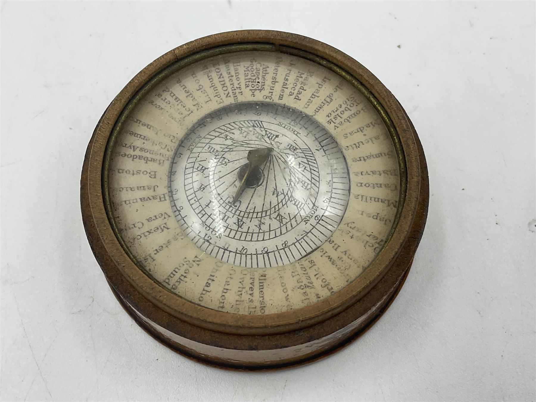 19th century pocket sundial compass pantochronometer, central sun dial pivoting with angled gnomon, within a broad enamelled band, listing world cities, paper calendar label to cover