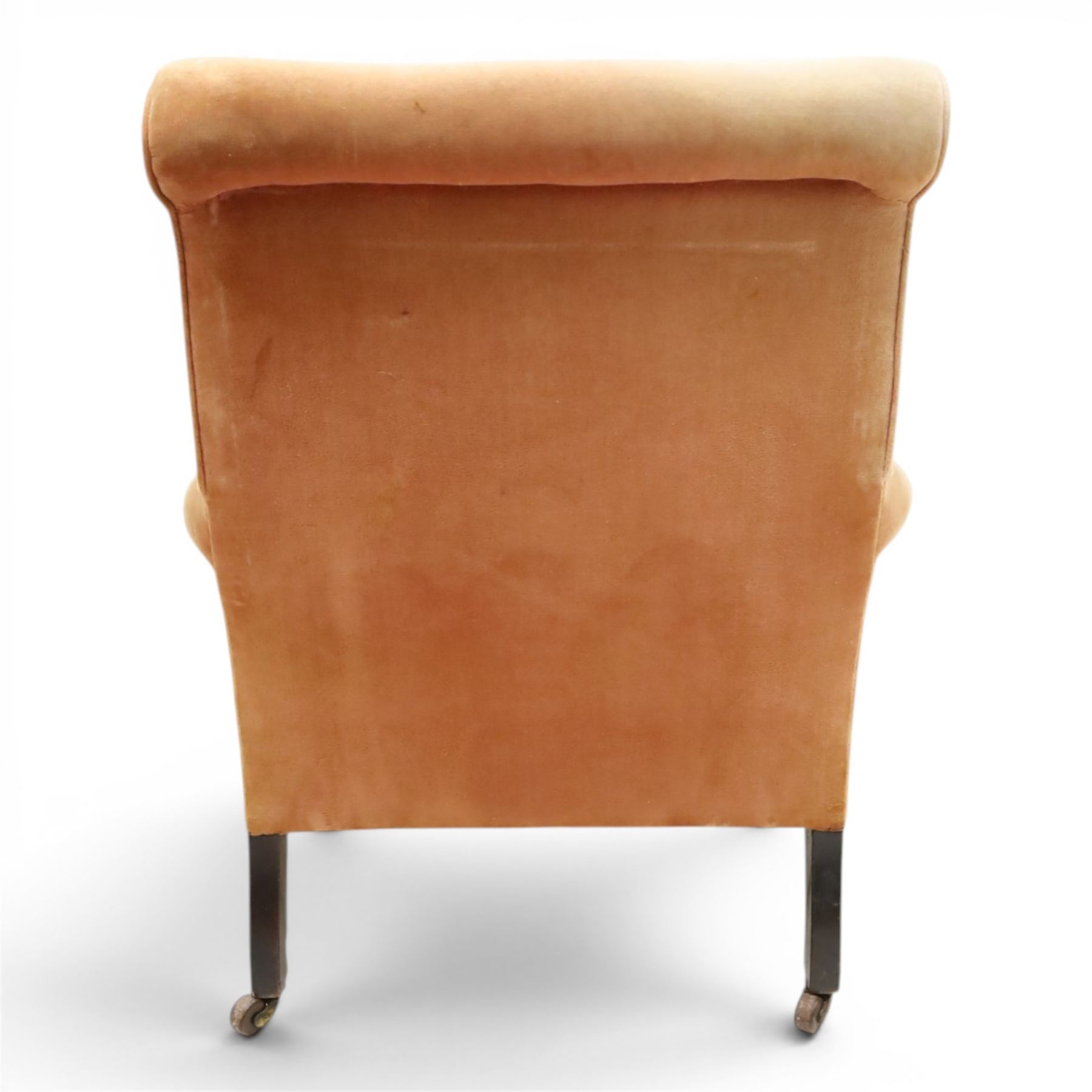 Victorian mahogany framed armchair of traditional shape, the high sprung rolled back over out-swept arms, deep sprung seat over turned feet with ceramic castors, upholstered in pale salmon pink fabric