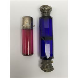 Late Victorian silver mounted ruby glass cylindrical scent bottle, with interior glass stopper, Birmingham 1900, makers mark worn, H8cm, together with a Victorian double ended cut blue glass perfume bottle mounted with white metal screw and flip caps decorated with foliate repousse detailing, H13.5cm