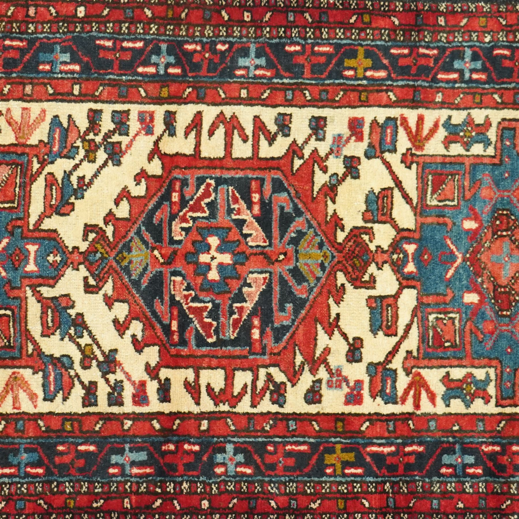 Caucasian Shirvan hand-knotted runner, ivory field decorated with a vertical sequence of bold hexagonal and lozenge medallions, each enclosing stylized geometric motifs, flanked by angular floral latch-hook devices, field dominated by madder red  and ivory with subsidiary colours of indigo, brown, and turquoise, with fringe ends   