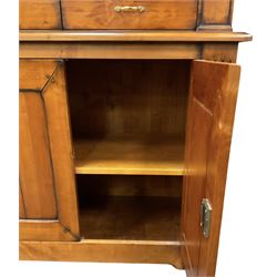 French cherry wood bookcase on cupboard, projecting moulded cornice over three shelves and two small drawers, the cupboard enclosed by two panelled doors flanked by fluted uprights