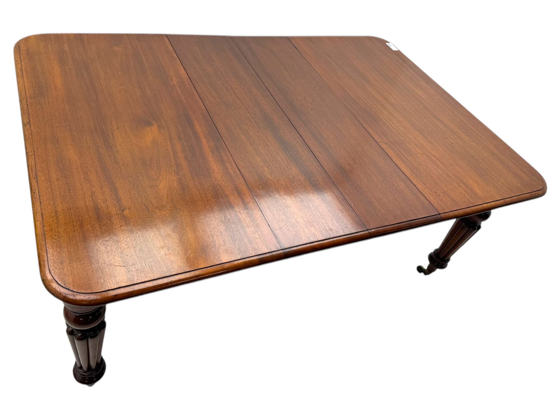 
Late Victorian mahogany extending dining table and four chairs, rectangular top with rounded corners and moulded edge, fitted with two additional leaves, raised on turned and reeded legs with brass castors, with a pair of Victorian mahogany hall chair, with curved top rail and plain splat, padded seat in textured salmon pink fabric, raised on turned and tapering front legs and another pair of early 20th century mahogany dining chair, with shield back and carved pierced splat, serpentine seat rail with striped upholstered cushion, raised on moulded square front legs