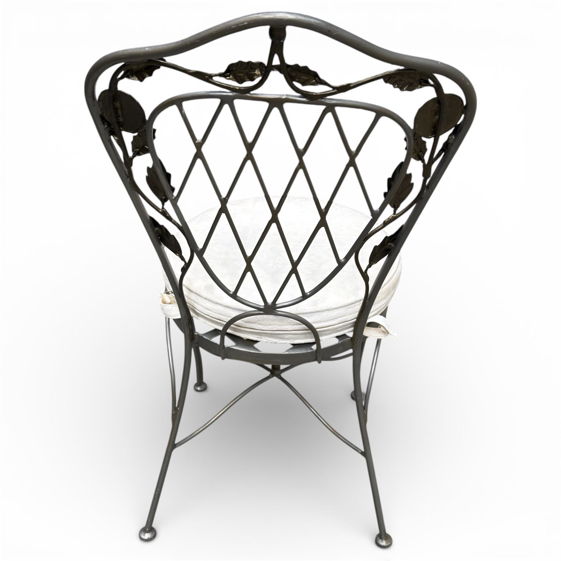 Wrought iron garden dining table with leaf decoration, and set of four matching chairs