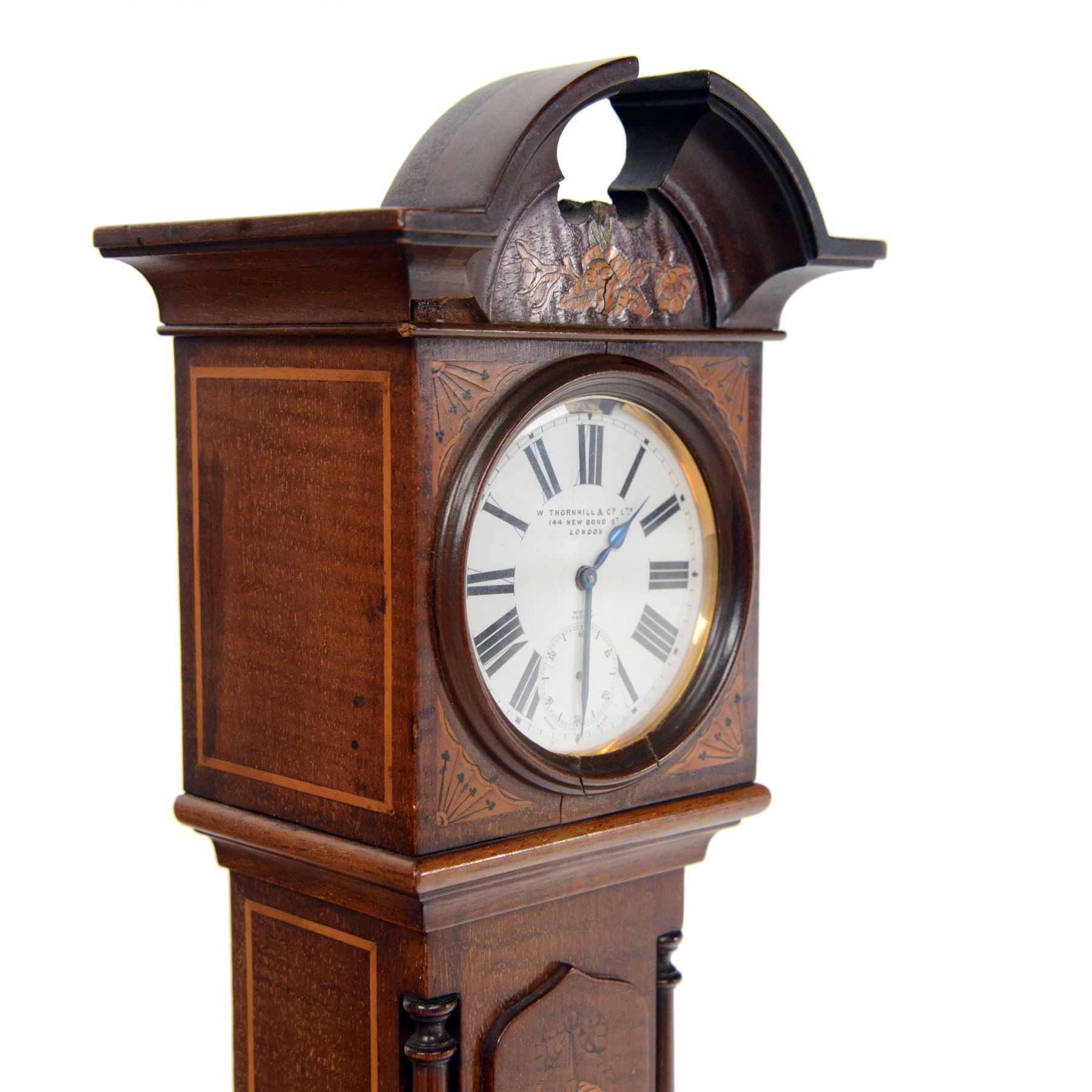 Edwardian mahogany and marquetry miniature longcase clock, the case with ogee top, over arched door flanked by turned columns, the base, door and top with classical urn and floral marquetry detail, housing goliath pocket watch, the white enamel dial with Roman numerals, chapter ring and subsidiary dial, and marked W. Thornhill & Co Ltd 144 New Bond St London, H38cm