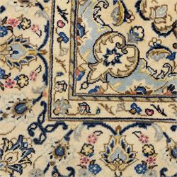 Central Persian Kashan hand-knotted carpet, ivory ground, with a central pale blue shaped floral medallion with pendants, surrounded by scrolling foliate and floral motifs incorporating rosettes, palmettes and delicate vine work in blue, cream and beige tones, enclosed by an ivory border with repeating palmettes and meandering vines, flanked by floral guard stripes, with cotton fringes