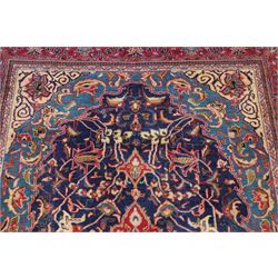 North West Persian Sarouk hand-knotted rug, indigo field with central stepped medallion with pendants, issuing an all-over arrangement of scrolling vinery, palmettes and stylized floral sprays, enclosed by a broad turquoise field of sinuous arabesques,, ivory spandrels with foliate decoration, madder red main border of stylized palmettes, and flowering vines, flanked by reciprocal guard stripes, cotton fringe ends 