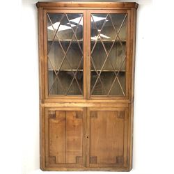 Large late 19th century sycamore corner cabinet, the top section with two astragal glazed doors enclosing two shaped shelves, the lower section enclosed by two panelled doors with square spandrels, W128cm, H215cm