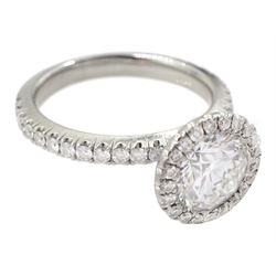 De Beers Aura platinum round brilliant diamond ring, the central diamond solitaire of 1.07 carat, clarity VVS2, colour E, with GIA certificate, surrounded by halo of diamonds and diamond set shoulders, total diamond weight 1.46 carat boxed with authenticity card and purchase receipt dated 2017