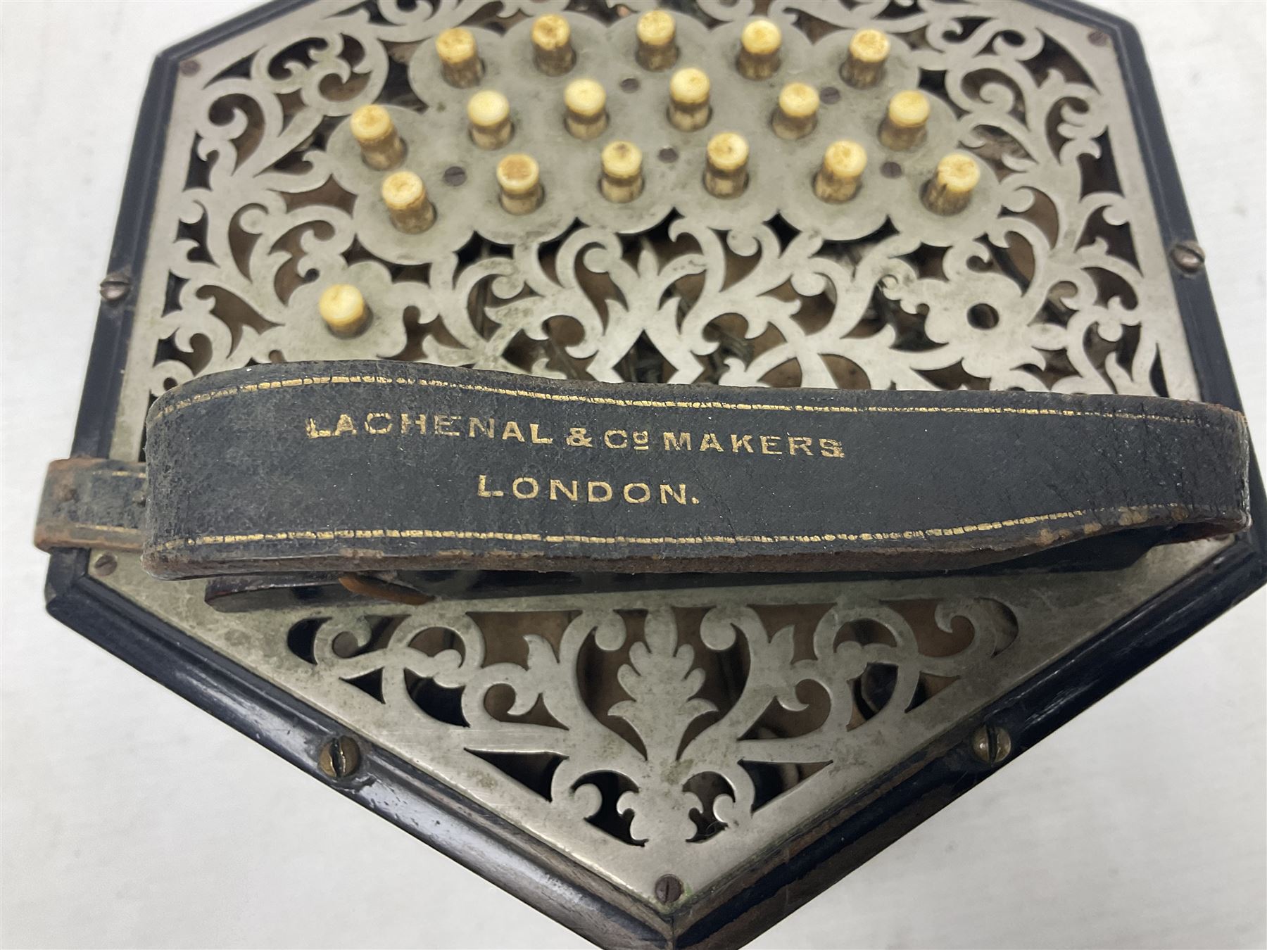19th century Lachenal concertina of hexagonal form with fretworked nickel ends and thirty-four plus one bone buttons; straps marked Lachenal & Co Makers London and wooden handle stamped English Make Trade Mark L16cm