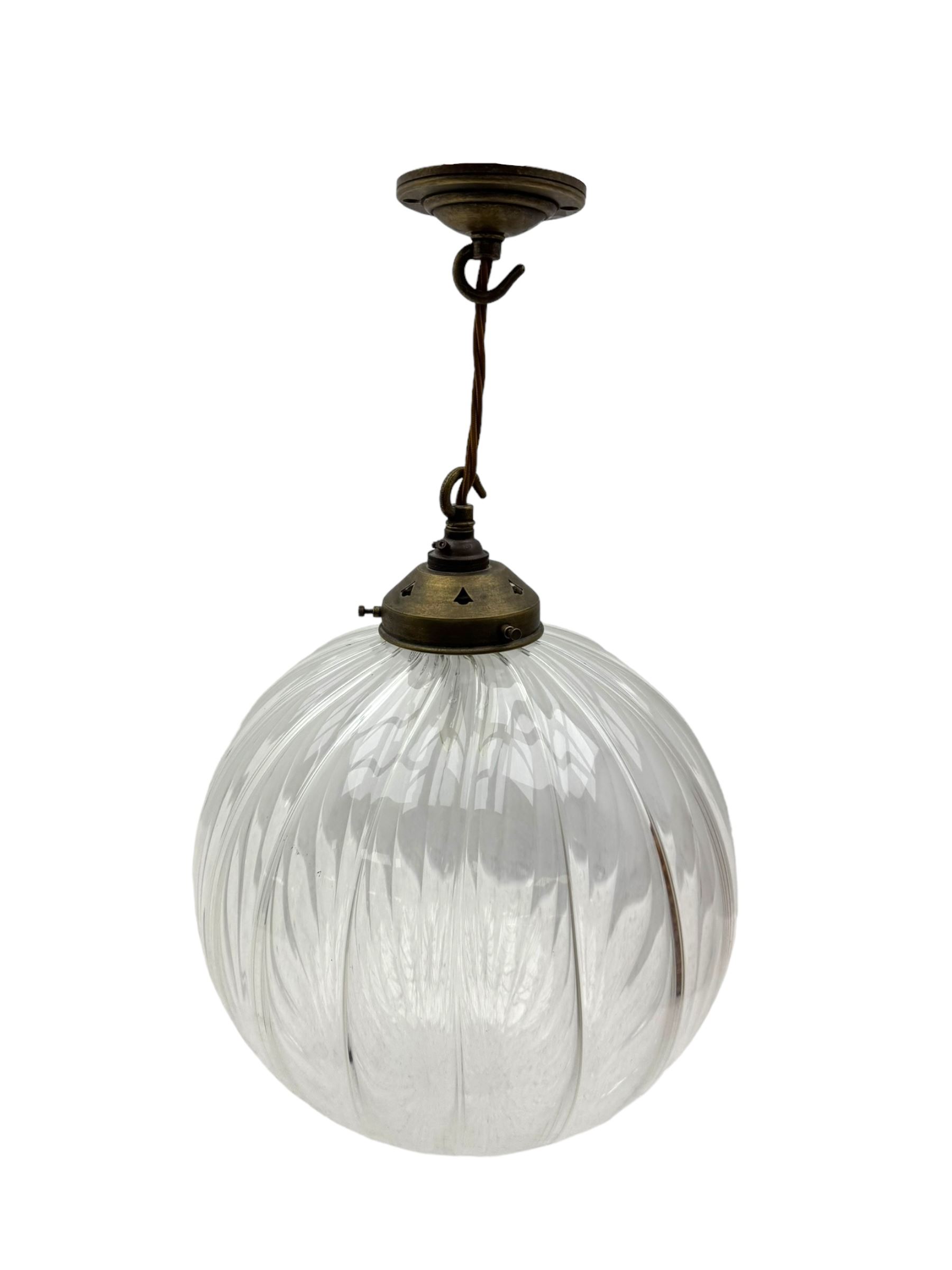 Set of two small and two large pendant lights, each with clear glass spherical shade with moulded swirl pattern, suspended from twisted cords, brass ceiling rose