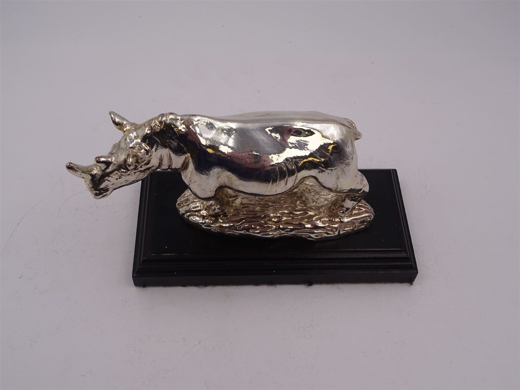 Filled silver model of a rhinoceros by Afrisilver, upon lacquered wooden base, H11.5cm