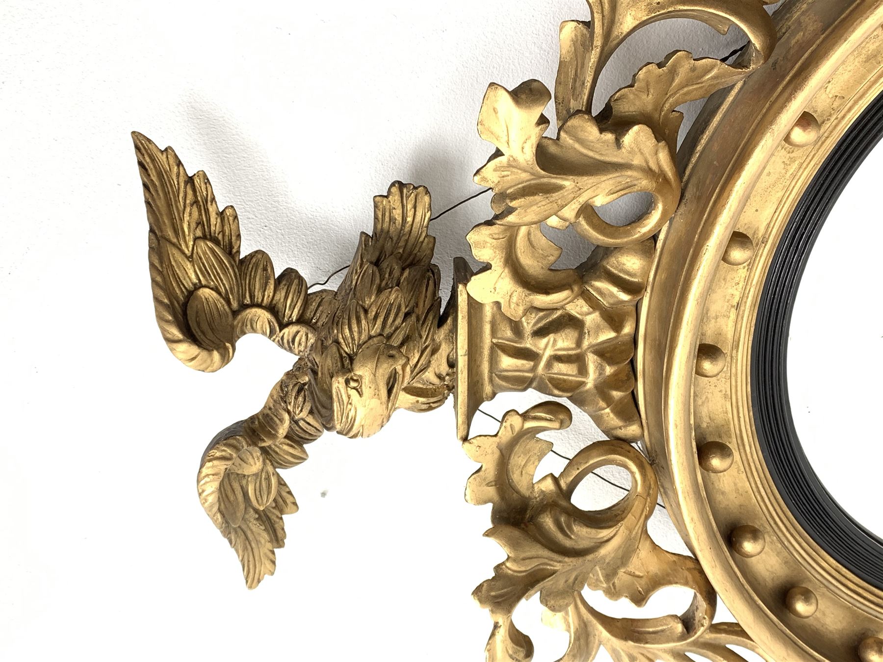 Large Regency carved wood and gesso circular convex mirror, eagle pediment on platform flanked by acanthus leaf scrolls, moulded surround and ebonised slip