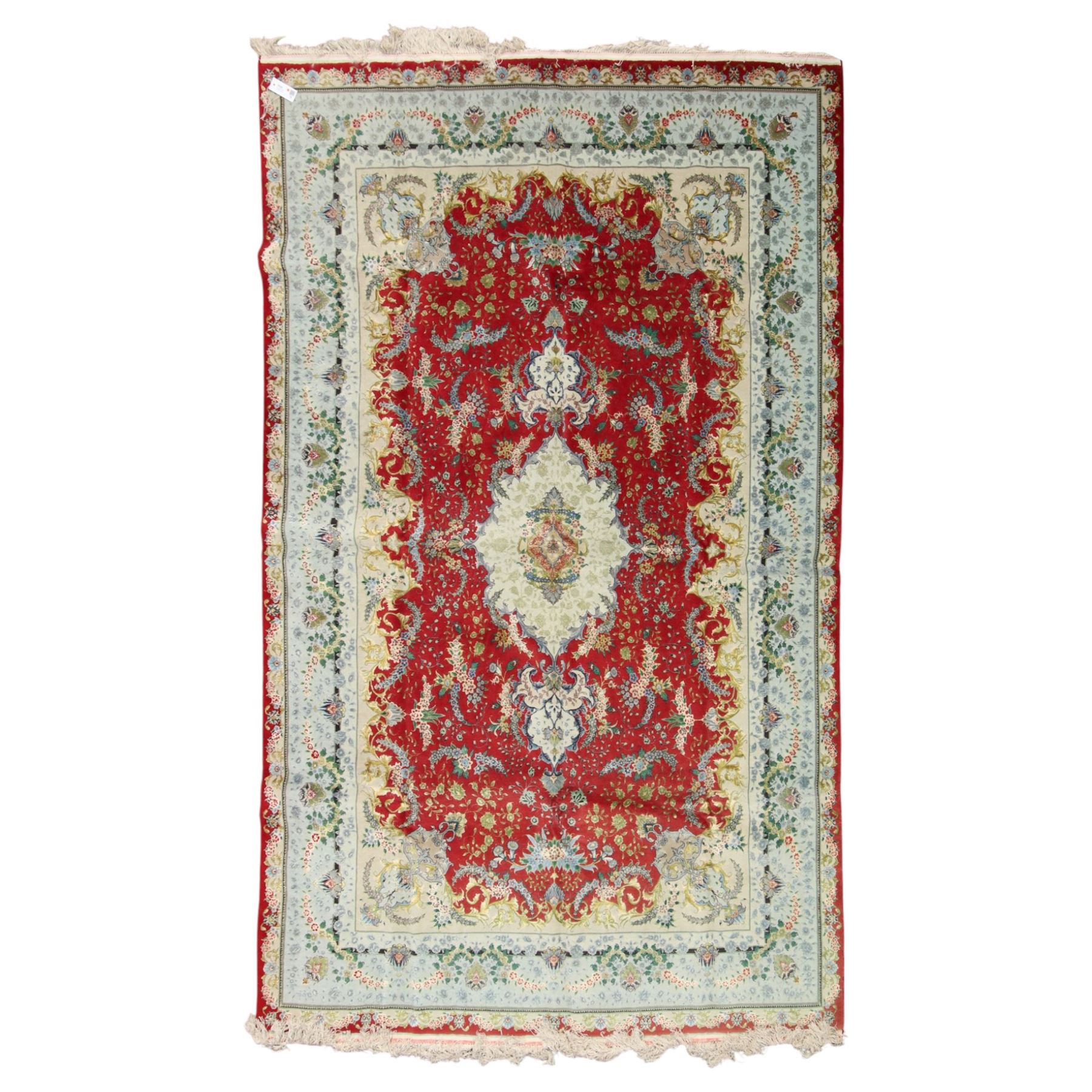 Persian silk inlaid crimson ground Kashan rug, the central shaped field with a floral pole medallion surrounded by trailing floral motifs and festoons of flowerheads, the wide cyan guard line with repeating palmettes and scrolling floral vines