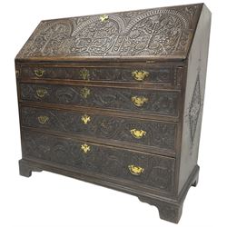 18th century heavily carved oak bureau, the fall front relief carved with three arches enclosing plants and flower head decoration, the interior fitted with pigeonholes, drawers and cupboard, four graduating cock-beaded drawers below, carved with lunettes and trailing foliage decoration, on bracket feet