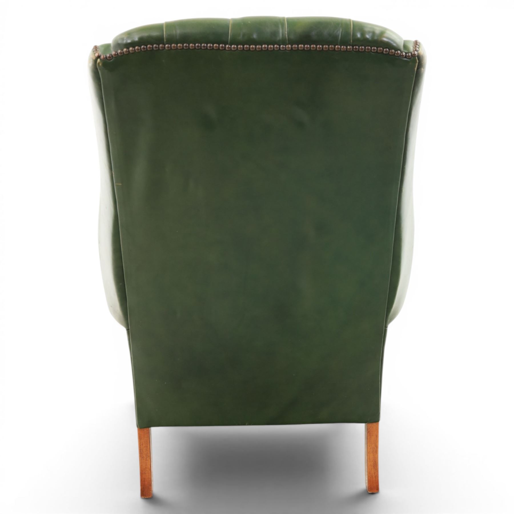 20th century green leather wingback button backed armchair, brass studded trim, with scrolled arms raised on oak supports