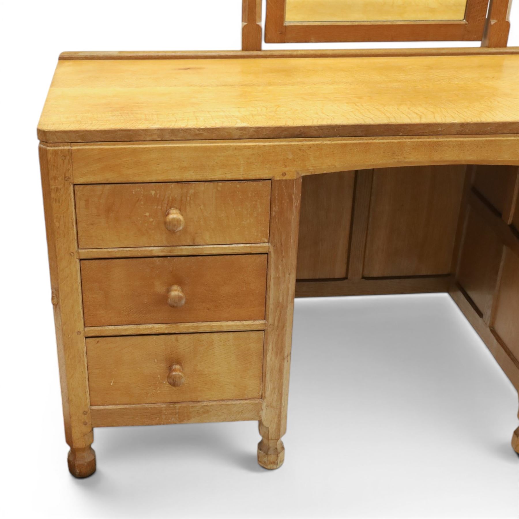 Mouseman - adzed oak kneehole dressing table with mirror, the rectangular adzed top with raised back and canted corners with fixed central pivoting mirror with scallop-carved cresting rail, over an arched recessed kneehole flanked by three graduating drawers to each side with turned knob handles, raised on octagonal feet, with carved mouse signature, by the workshop of Robert Thompson of Kilburn