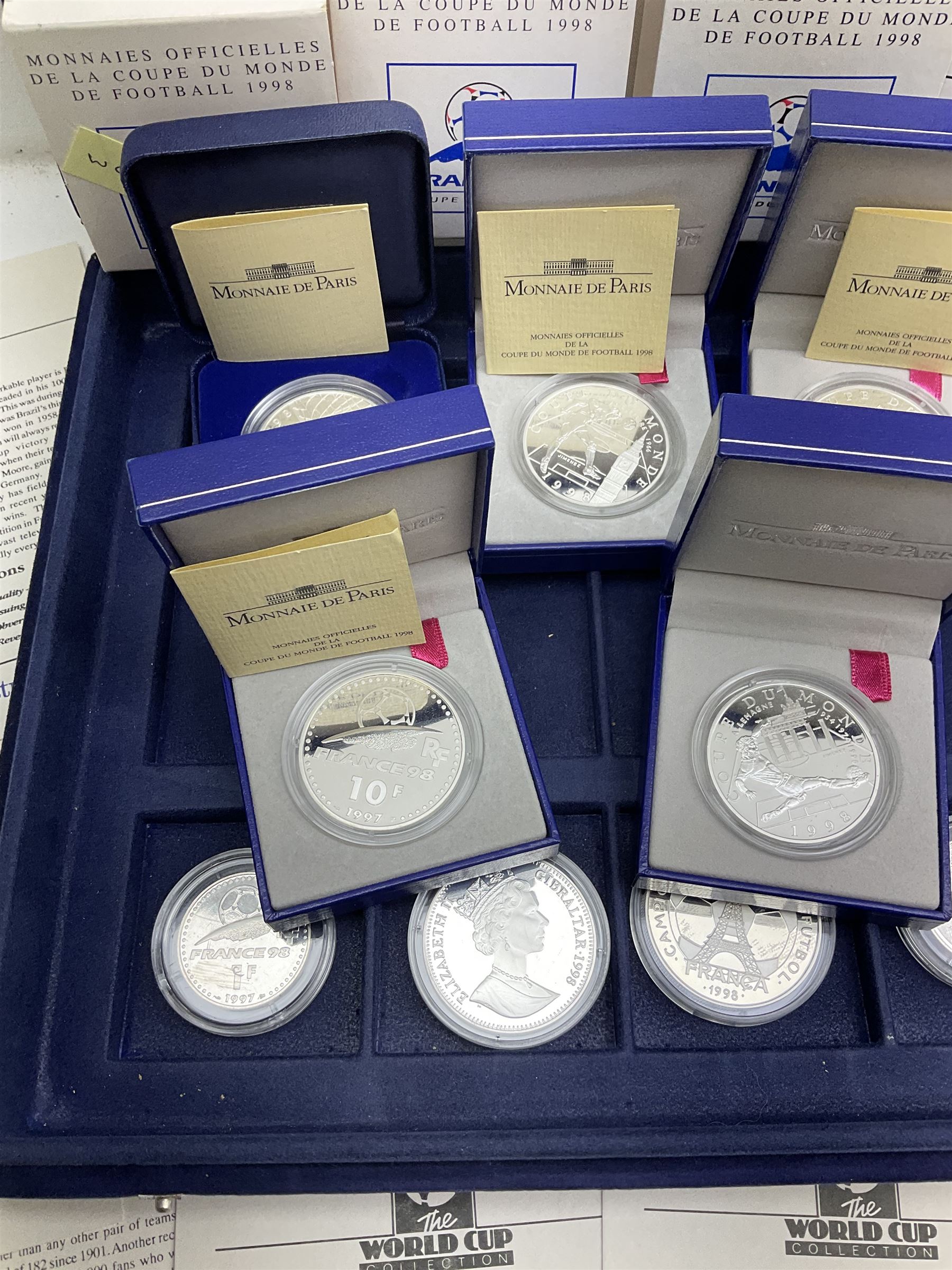Nine commemorative coins relating to the France 1998 World Cup, some cased with certificates, in a blue coin storage box
