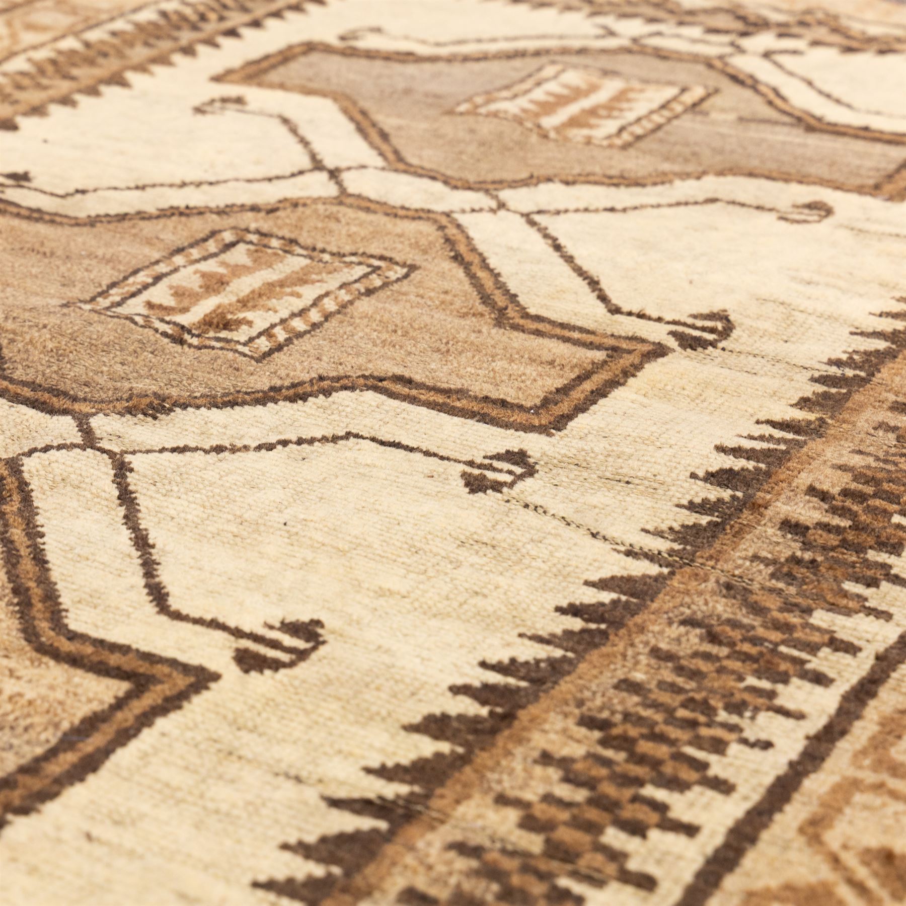 North West Persian Gabeh hand-knotted rug, natural ivory field with a vertical sequence of three large stepped geometric medallions in soft shades of brown and taupe, each enclosing stylized tribal motifs, flanked by narrow guard borders incorporating chevron and zigzag designs, with fringe ends 