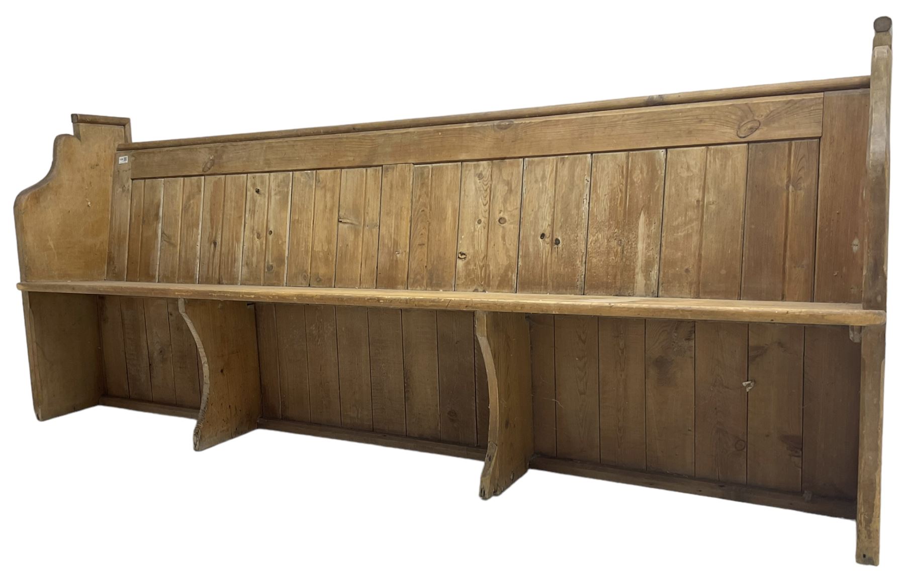 Early 20th century pine church pew, vertical plank back over rectangular seat, flanked by shaped end supports, with bible rest to back