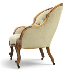 Victorian carved walnut framed armchair with matching stool, the tub-shaped chair with moulded and shaped frame and arm terminals, raised on scrolled cartouche carved supports with scroll feet and castors, buttoned back and sprung seat upholstered in sage green fabric; the small circular footstool with buttoned seat and scroll supports (W36cm H15cm)