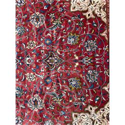 Northwestern Persian Lillihan hand-knotted carpet, madder red field with scrolling vines, rosettes, and palmettes around a central circular medallion in navy, ivory and ochre, and ivory ground spandrels within a navy border of stylized flowerheads and vines between multiple guard stripes 
