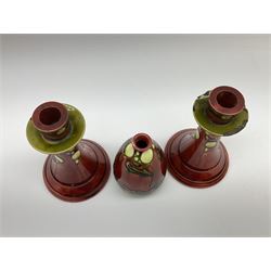 Minton Secessionist vase, with tube-lined stylised flower head decoration upon a red and green ground, printed mark to base 'Minton Ltd, No. 31', together with a matching pair of Minton Secessionist candle sticks, candlestick H17cm