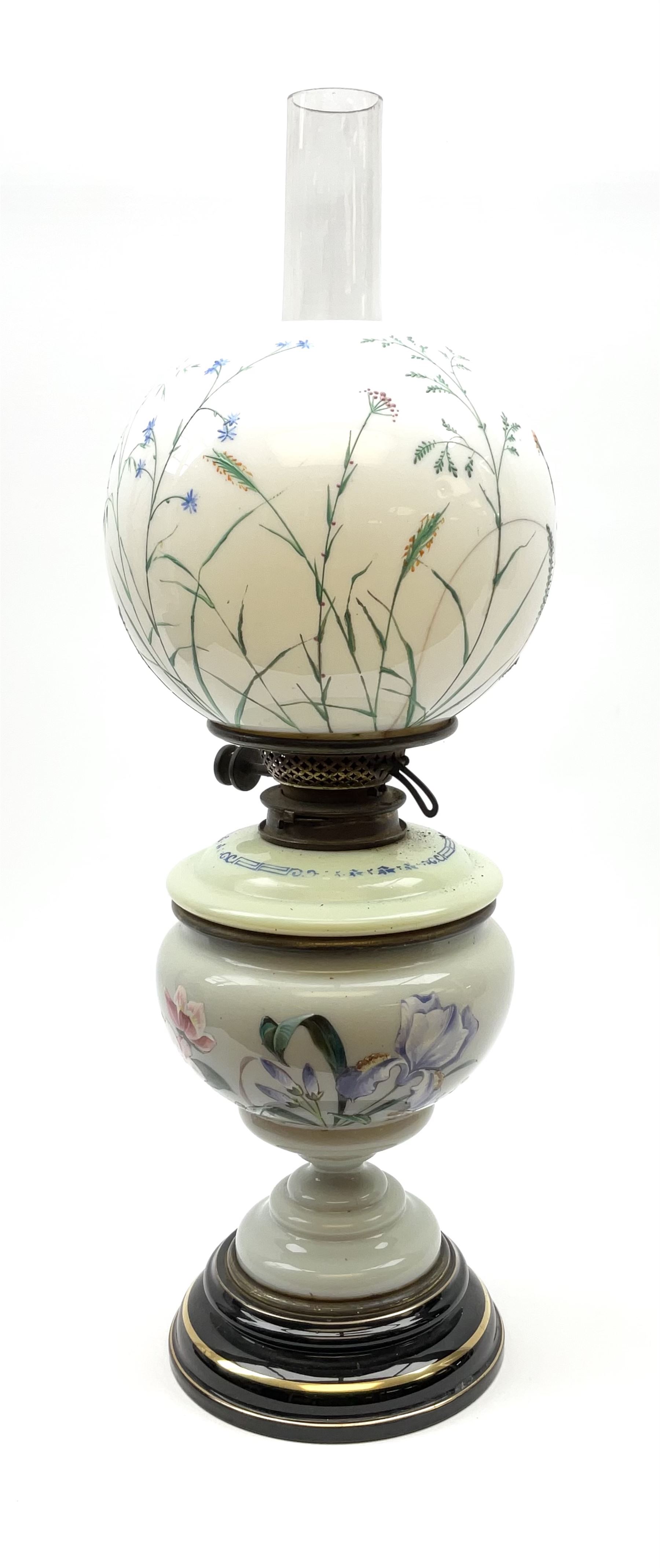 A Victorian oil lamp, with opaque glass reservoir hand painted with flowers beneath a Hinks burner and supporting a globular floral painted opaque glass shade and glass chimney, H47.5cm. 