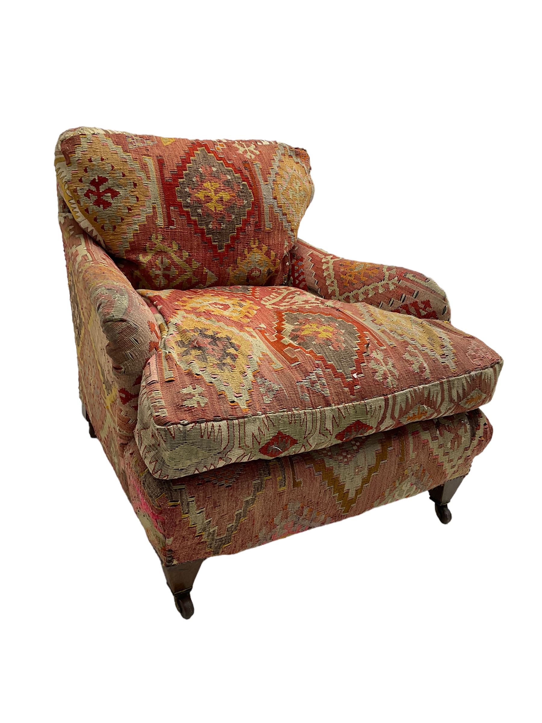 Early 20th century Howard style armchair, upholstered in Kilim fabric with sprung seat, hardwood frame, square tapering supports with brass and ceramic castors