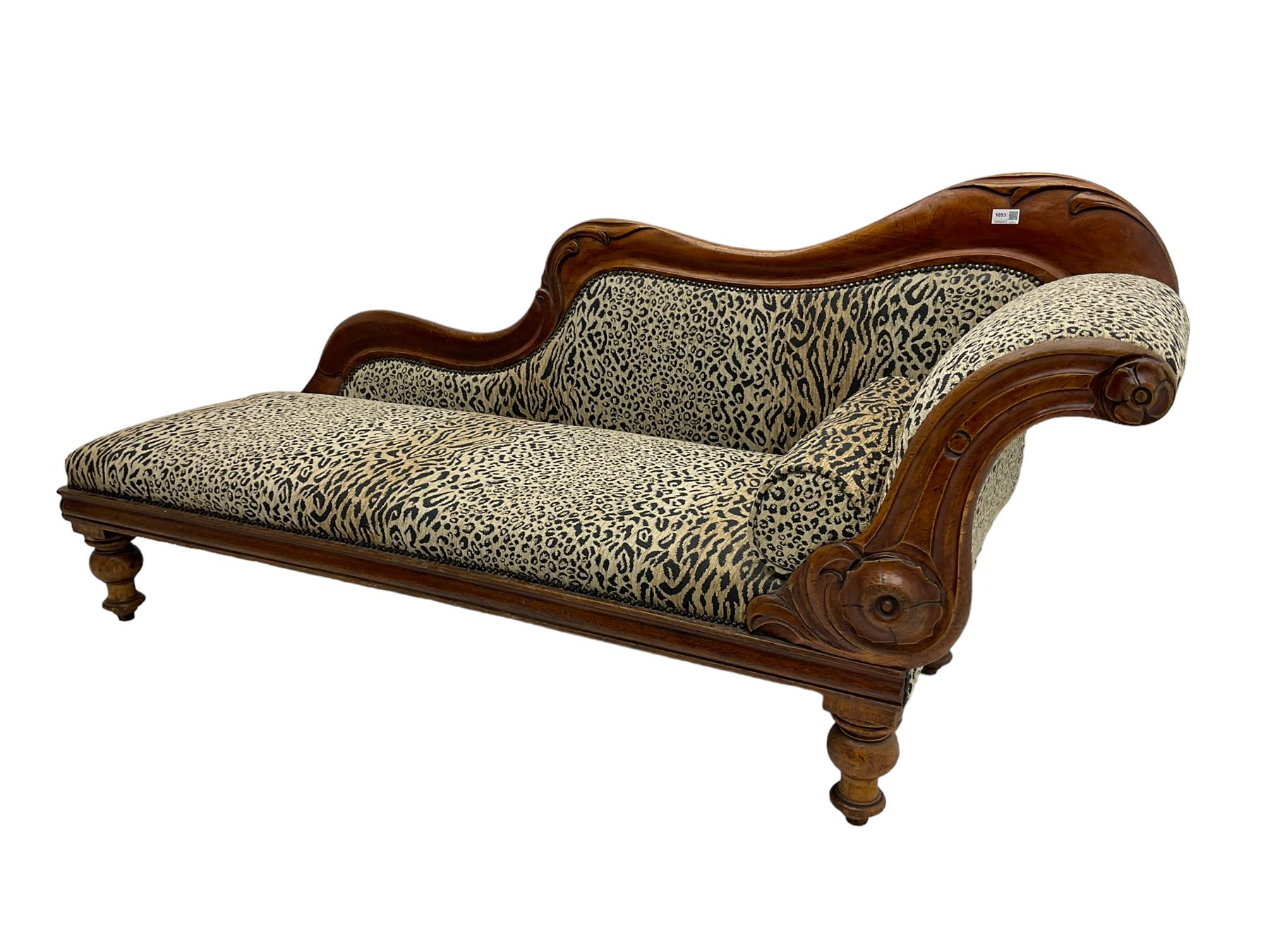 Victorian mahogany framed chaise longue, shaped arm carved with acanthus leaves, the scrolled back with applied carved rosettes,upholstered in monochrome leopard print fabric with bolster cushion, raised on turned supports