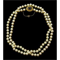 Single strand cultured cream / pink pearl necklace, on a gold cabochon garnet clasp, stamped 9ct
