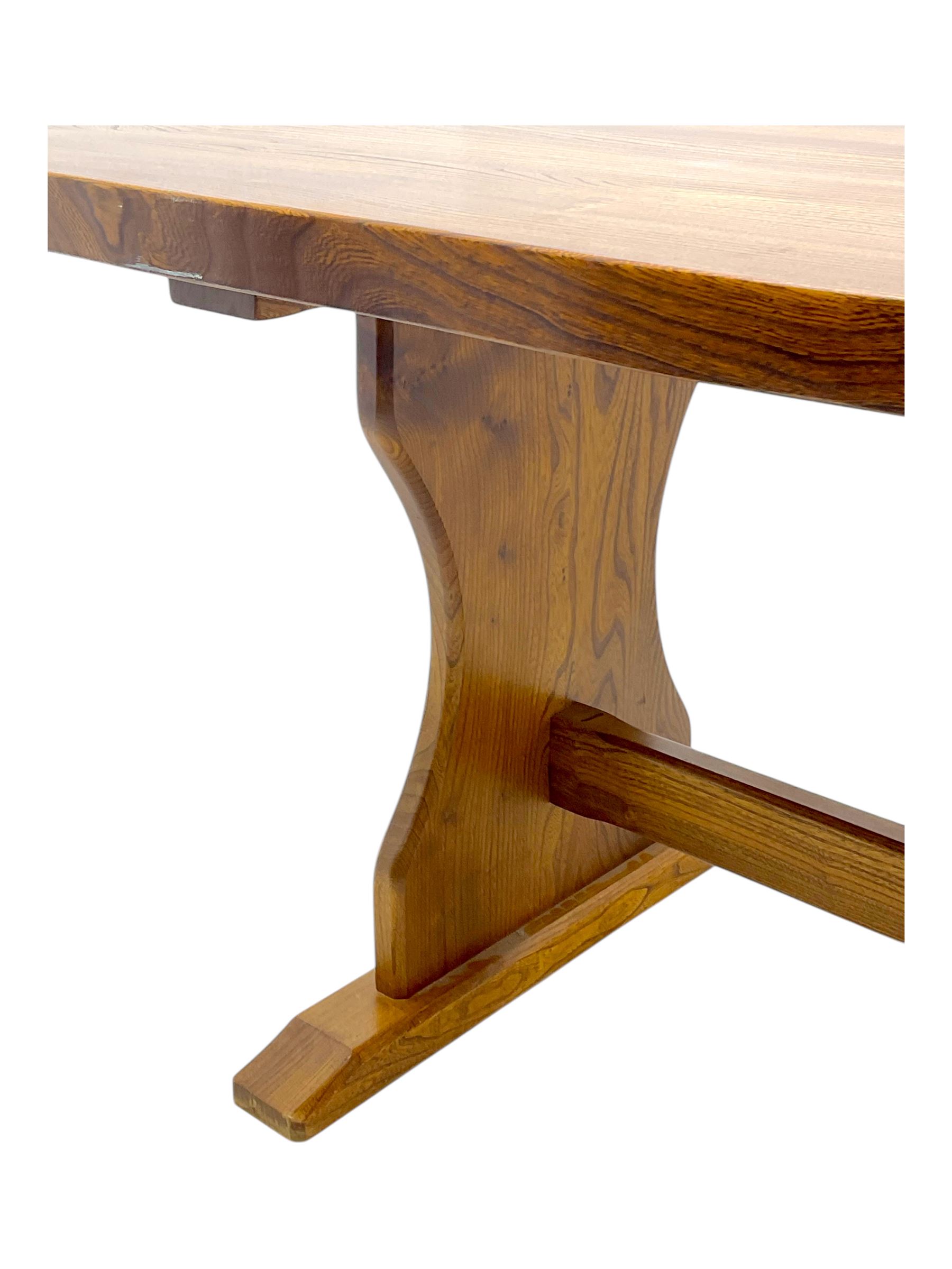 Late 20th century oak trestle table, rectangular top with naturalistic edge, supported by two curved pedestal bases united by central stretcher, on block feet