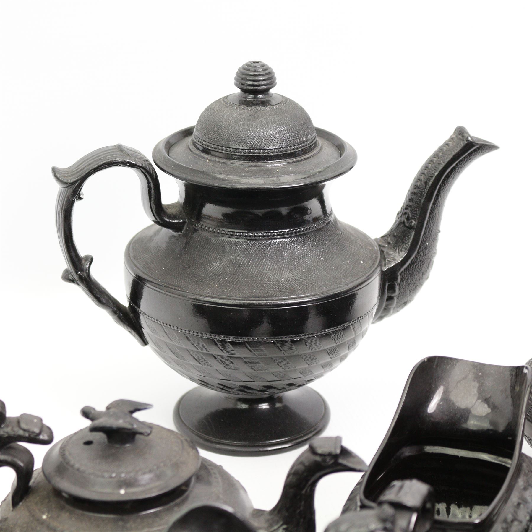 Early 19th century and later black basalt tea wares, mostly with relief or engine-turned bodies, including a Cyples bachelors teapot, other teapots, jugs etc in one box