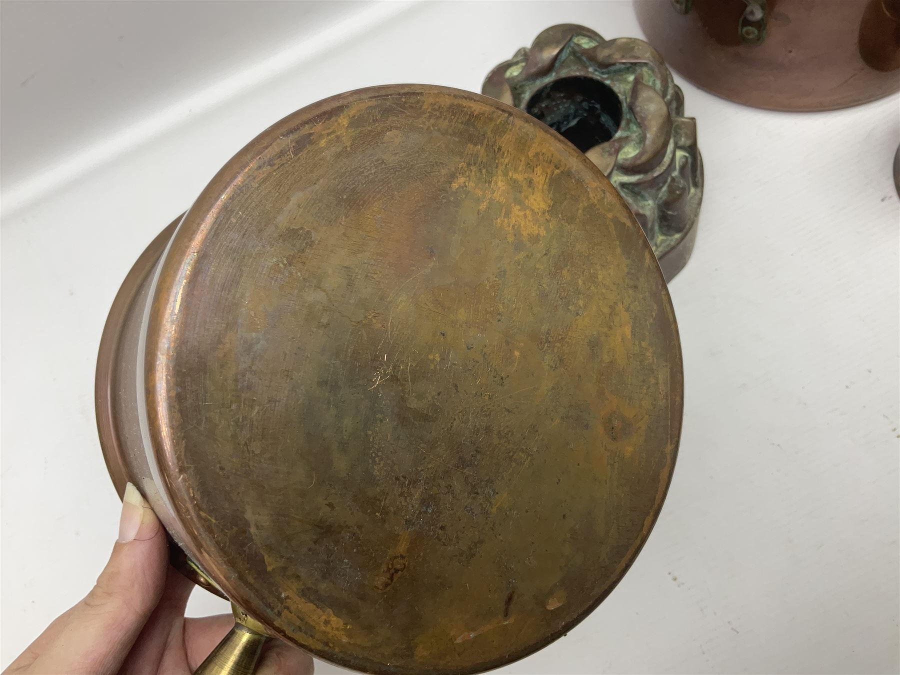 Four Victorian copper moulds, together with a graduating set of copper pans with wooden handles and finials to covers, largest pan 