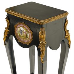 Early 20th century French ebonised sewing or work table, rectangular hinged top with foliate moulded gilt metal edge, enclosing upholstered interior, over a central Sevres style porcelain plaque depicting a courting scene, raised on cabriole supports with gilt metal carotuche and acanthus knee mounts, united by undertier with brass gallery terminating to gilt metal scroll feet