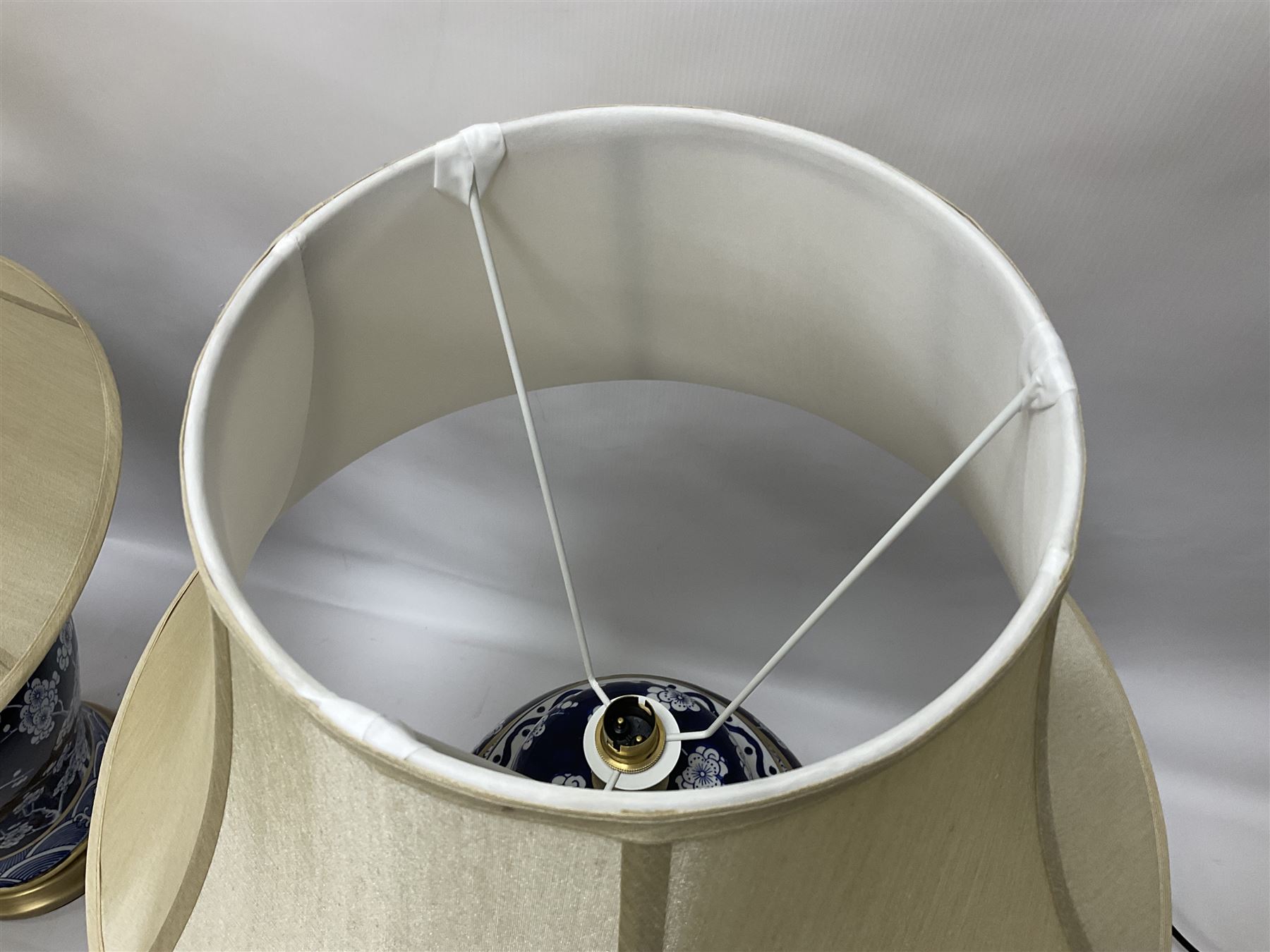 Pair of blue and white table lamps, each of baluster form, decorated with prunus blossom, within stylised borders, raised upon circular gilt base, excluding fittings H48cm