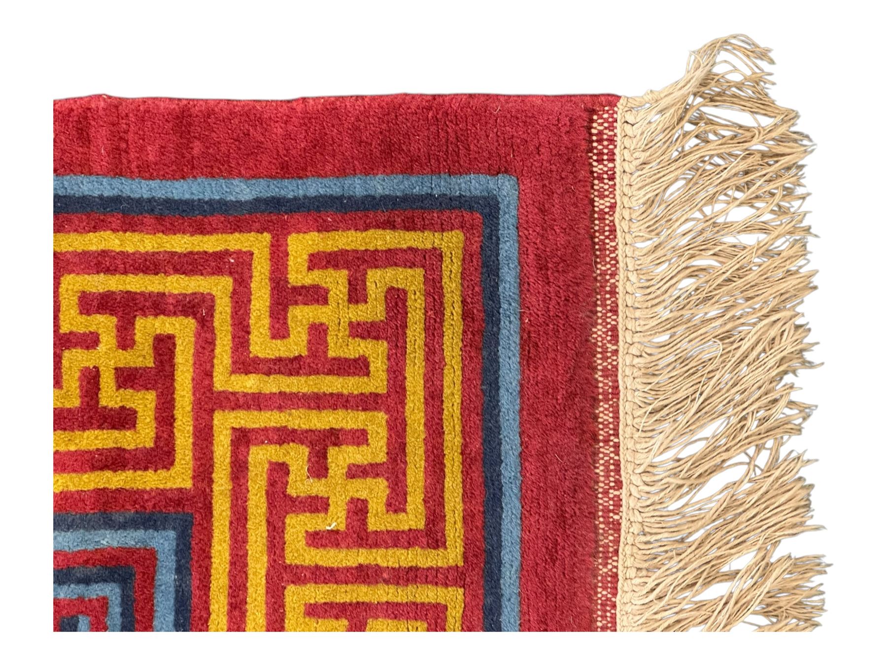 Tibetan-design handwoven rug, deep red field with three central medallions in yellow and blue, traditional yellow key border, white fringes on both ends