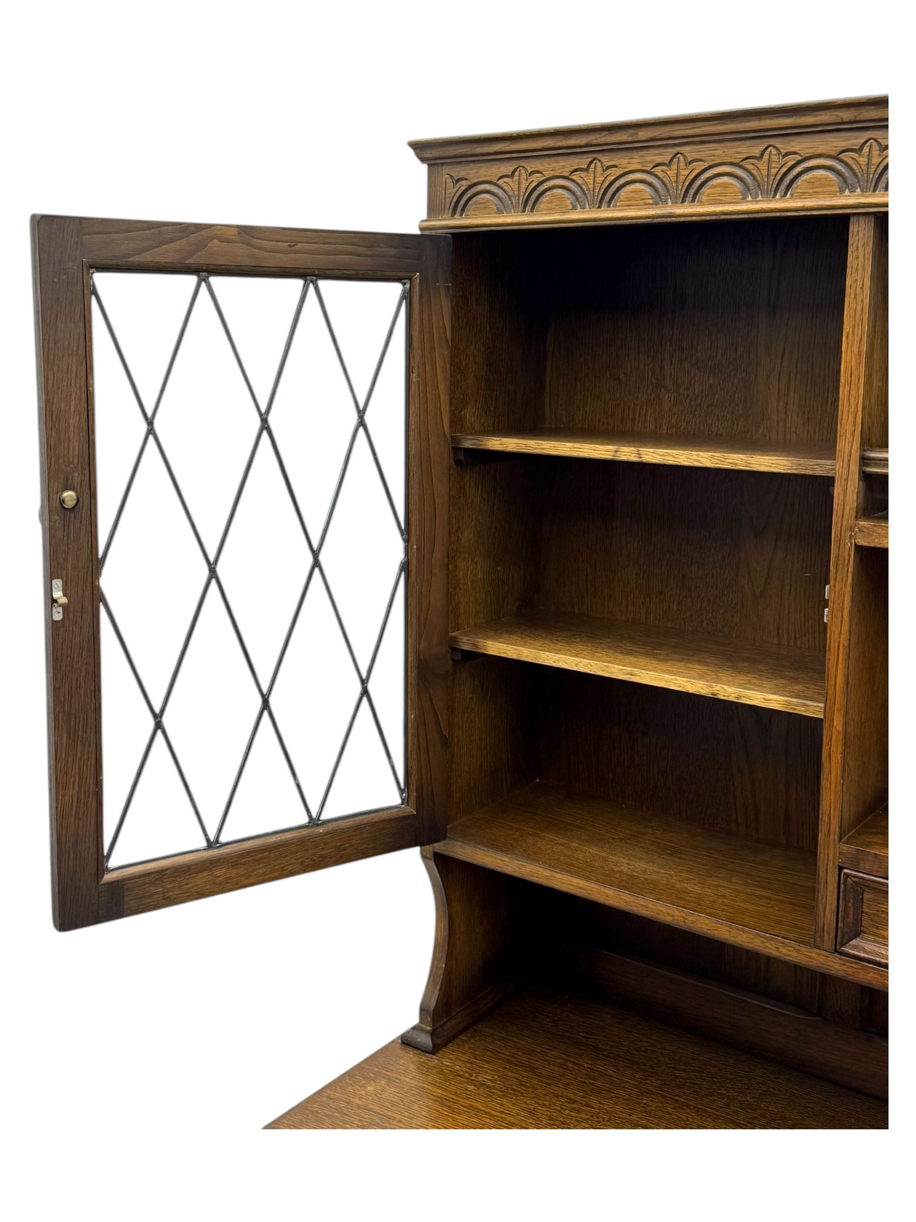 Large mid-20th-century oak dresser with two astragal glazed doors between gallery shelf and lower shelf, with three short drawers and lower section with four drawers and three double-panelled linen-fold hinged cupboard doors 