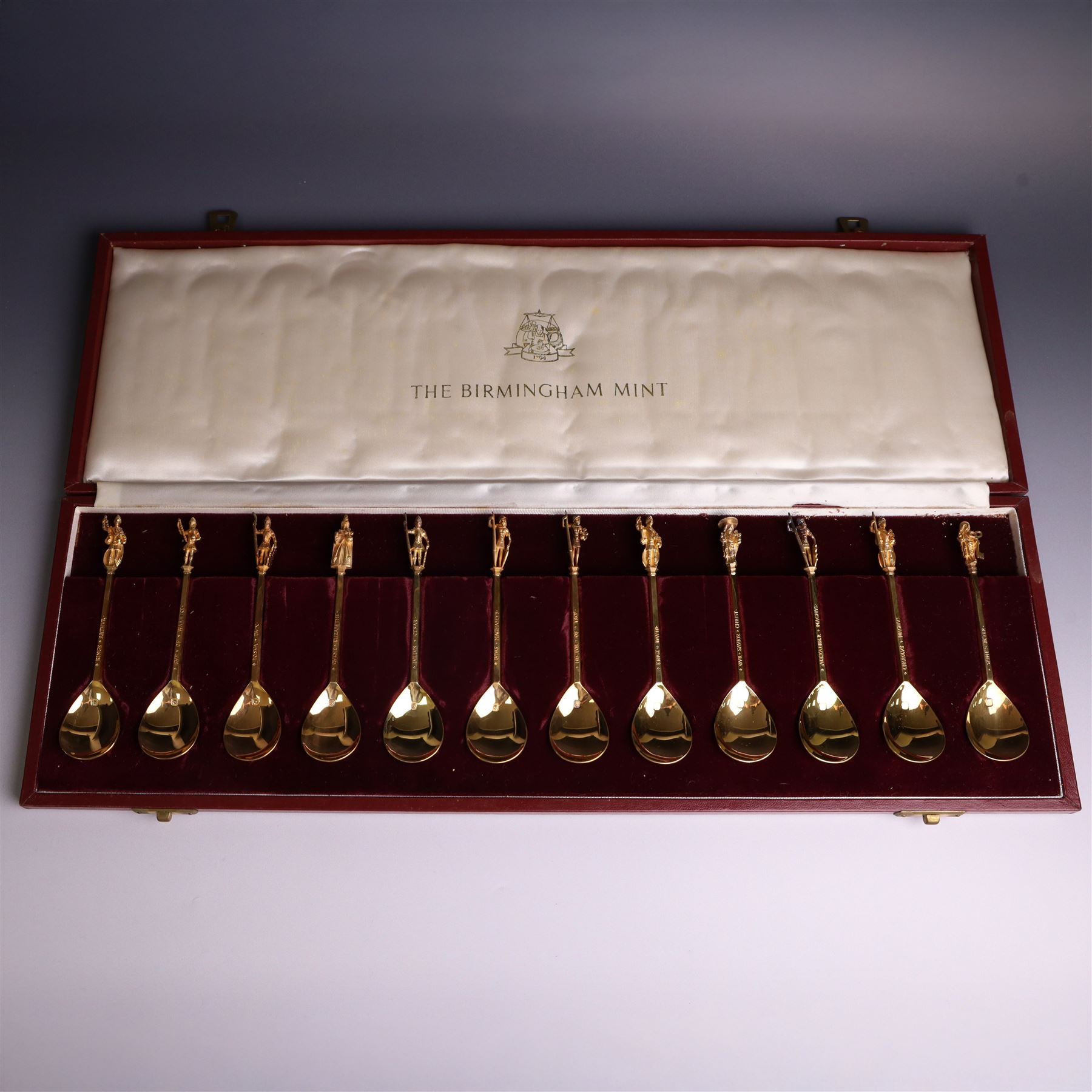 Set of twelve 'The Tichborne Collection' silver gilt spoons, each with fig shaped bowls, the finials depicting different historical figures including Queen Elizabeth, Hector of Troy and Saint Peter, hallmarked Birmingham Mint 1978, in fitted case
