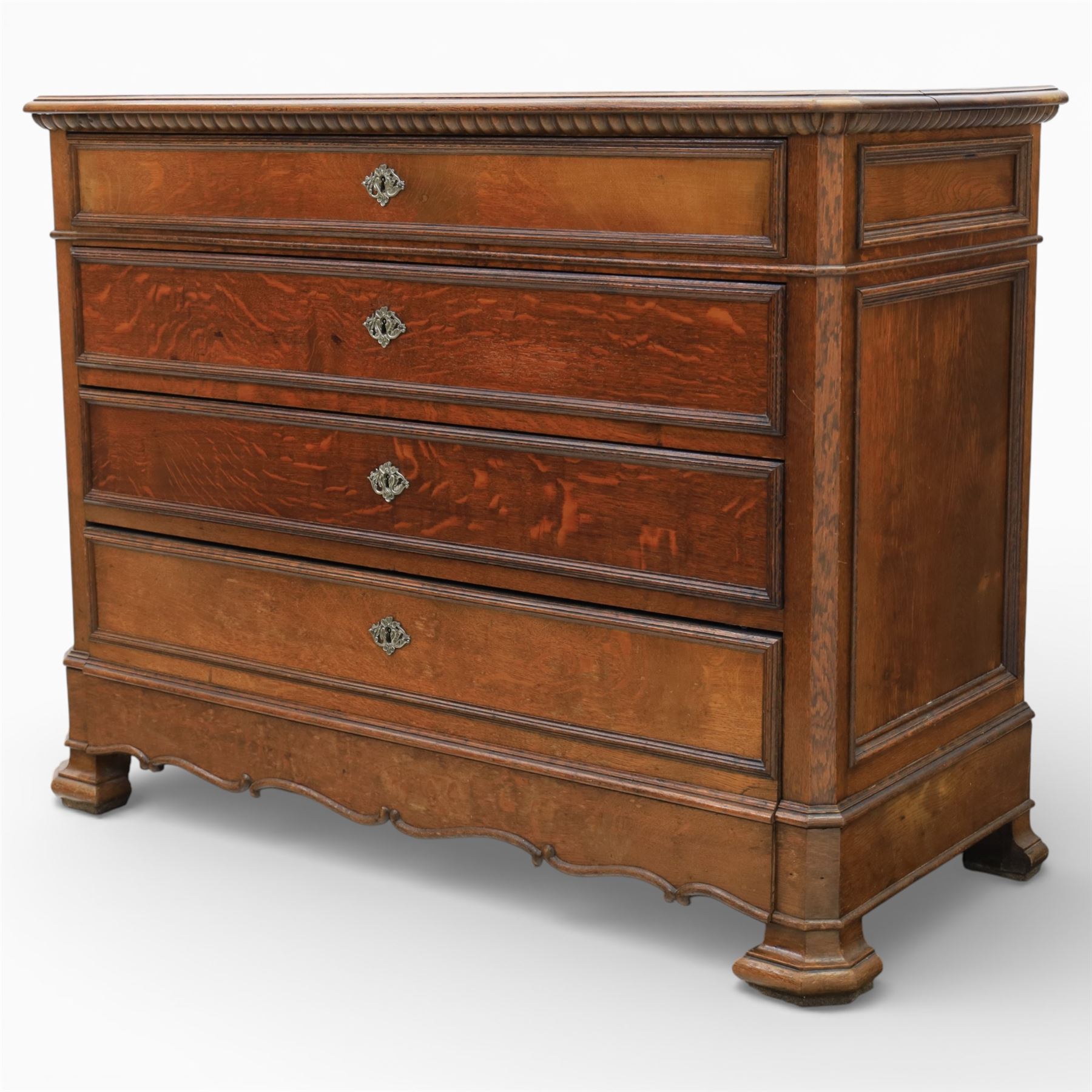 Late 19th century French provincial oak chest of drawers, moulded rectangular top with carved rope edge over four graduated long drawers with raised and fielded panels and ornate cast handles, canted angles and shaped apron below, standing on moulded block feet,